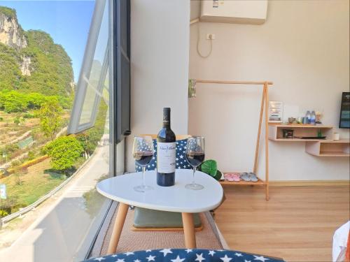 a table with a bottle of wine and two glasses at Sure I Do全景山宿 in Yangshuo