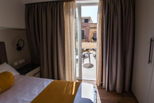 a bedroom with a bed and a door to a balcony at City Stay B&B in Taʼ l-Imgħajjen