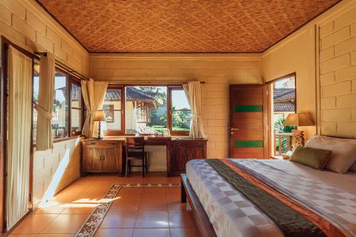 a bedroom with a bed and a desk at Munari Resort Ubud in Ubud
