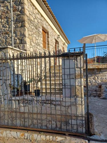 a gate to a stone house with an umbrella at Το πέτρινο της Δώρας in Kakóvatos