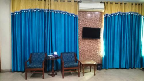 a room with blue curtains and a table and chairs at Hotel Rest INN in Lahore