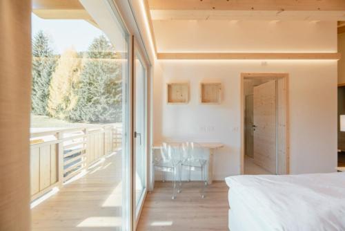a bedroom with a large window and a table and chairs at Garnì Aurora Bed and Breakfast in Soraga
