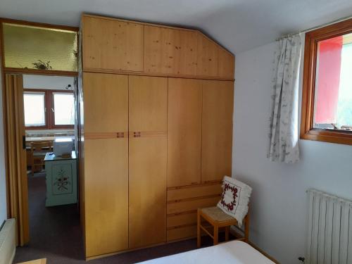 a bedroom with a large wooden cabinet and a chair at Piccolo Igloo in Falcade