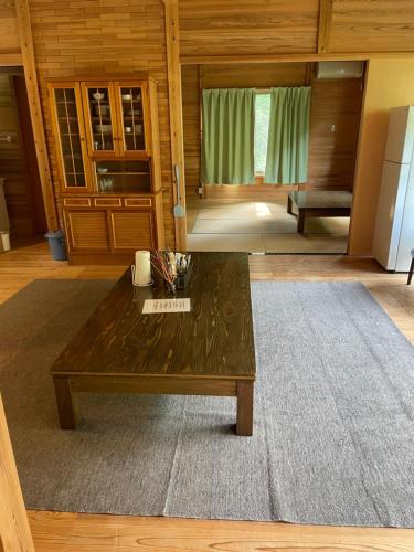 een woonkamer met een houten tafel en een tapijt bij YAMAYA BASE 1 in Ōkawamochi