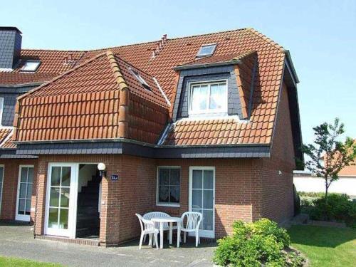 una casa de ladrillo rojo con mesa y sillas en Ferienwohnung Baade -KEINE MONTEURE-, en Friedrichskoog-Spitz