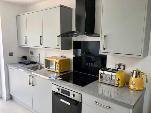 una cocina con armarios blancos y un aparato amarillo en la encimera en Crow Nest, en Barton-on-Sea