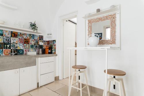 a kitchen with two stools and a mirror at Dimore del TEMPO PERS0 Prima Luce in Ostuni