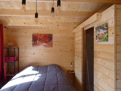 eine Holzhütte mit einem Bett in einem Zimmer in der Unterkunft Chanterelle in Comblessac