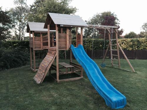 a playground with a slide and a play house at Kendall Lodge in Burwell