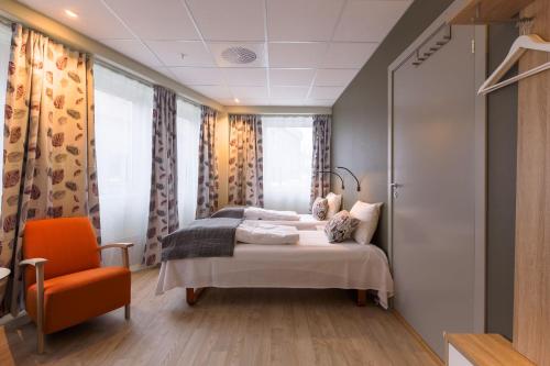 um quarto com uma cama e uma cadeira laranja em Corner Hotell em Brønnøysund