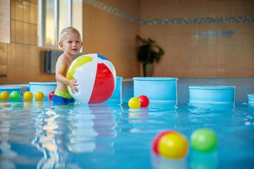 a young boy playing with a ball in a swimming pool at Hotel Slunce in Rýmařov