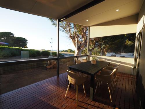 a wooden deck with a black table and chairs at Ardrossan Caravan Park in Ardrossan