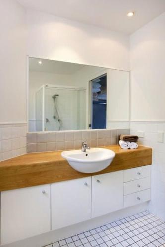 a white bathroom with a sink and a mirror at 3 Hilltop Villas White Water Views from the Heart of Sunshine in Sunshine Beach