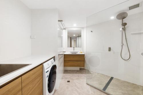 uma casa de banho branca com uma máquina de lavar roupa e um lavatório em 5 Pacific Outlook Ocean View Apartment in Sunshine Beach em Sunshine Beach