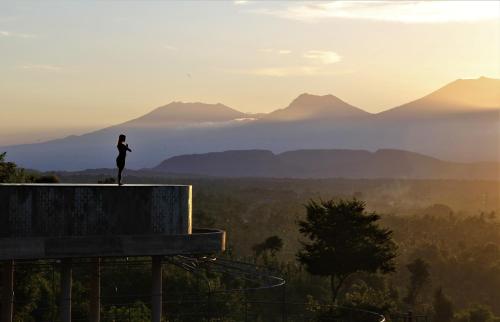 a woman standing on the edge of a building looking at the mountains at Sumberkima Hill 2 in Pemuteran