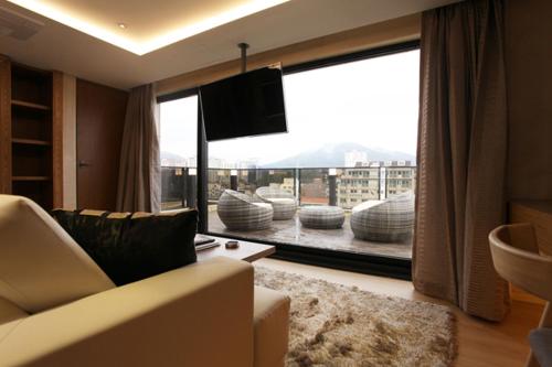 a living room with a couch and a large window at Jeju Cullinan Hotel in Jeju