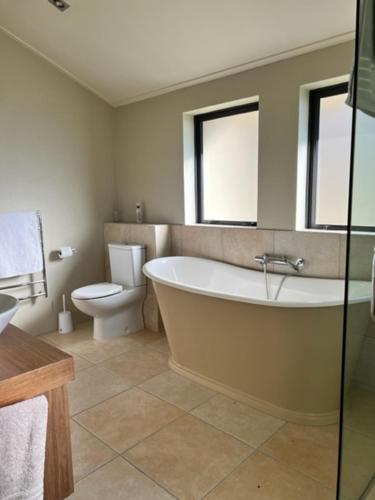 a bathroom with a bath tub and a toilet at Gibbston House Boutique B&B in Gibbston