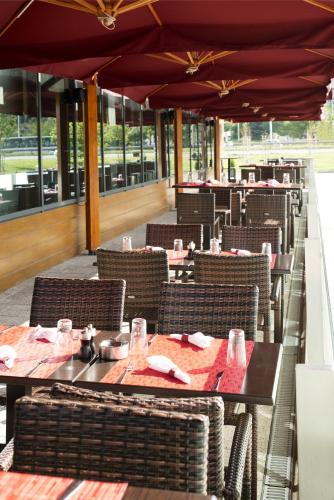 a dining room with tables and chairs and windows at Novotel Sofia in Sofia