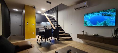 a living room with a table and a television on the wall at Penthouse Apartman Marčelina in Trogir in Trogir