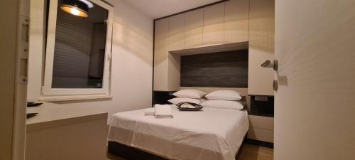 Cette petite chambre comprend un lit avec des draps et des oreillers blancs. dans l'établissement Penthouse Apartman Marčelina in Trogir, à Trogir