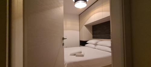 a bedroom with a bed with white sheets and a mirror at Penthouse Apartman Marčelina in Trogir in Trogir