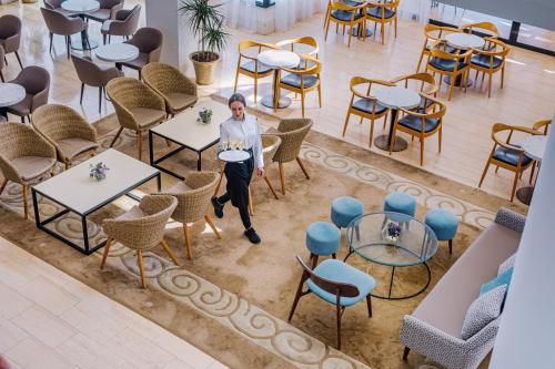 a woman standing in a room with tables and chairs at Louis Ledra Beach in Paphos City