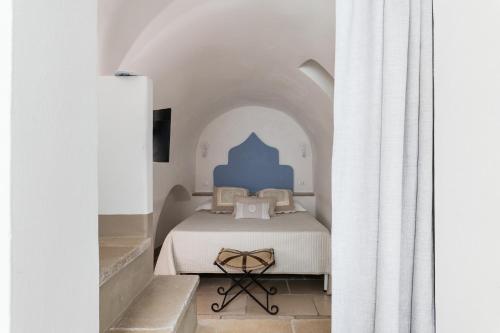 um quarto com uma cama num quarto branco em Dimore del TEMPO PERS0 Terrae Globus em Ostuni