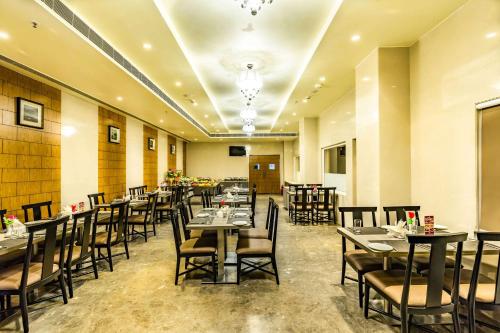 a restaurant with tables and chairs in a room at Quality Inn Ramachandra in Visakhapatnam