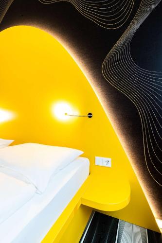 a yellow room with a bed and a light on the wall at Prize by Radisson, Bonn City in Bonn