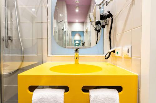 a yellow sink in a bathroom with a mirror at Prize by Radisson, Bonn City in Bonn