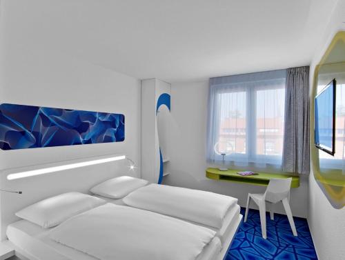 a bedroom with a bed and a table and a window at prizeotel Hamburg-City in Hamburg
