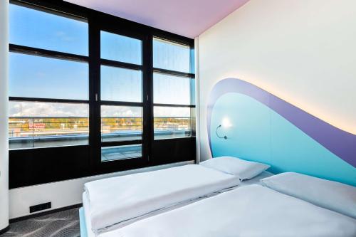 a room with two beds and a large window at Prize by Radisson, Rostock City in Rostock