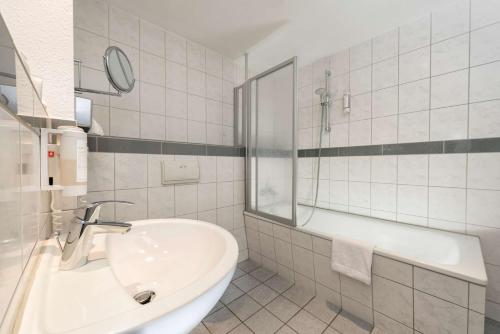 ein weißes Badezimmer mit einer Badewanne und einem Waschbecken in der Unterkunft Best Western Hotel Dortmund Airport in Dortmund