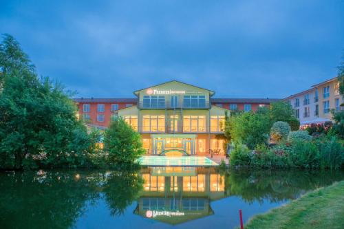 ein großes Gebäude mit einem Teich davor in der Unterkunft Best Western Premier Castanea Resort Hotel in Lüneburg