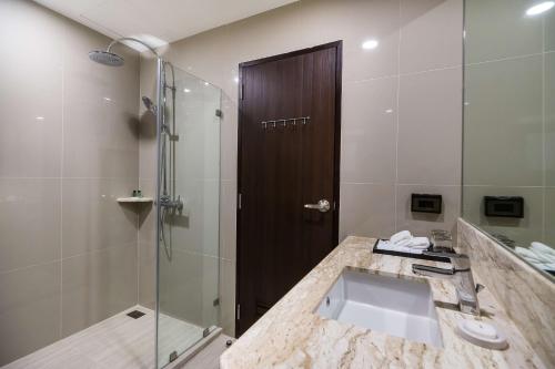 a bathroom with a sink and a glass shower at SureStay Plus Hotel by Best Western Sukhumvit 2 in Bangkok