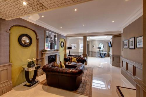 a living room with a leather couch and a fireplace at Best Western Plus The Connaught Hotel and Spa in Bournemouth