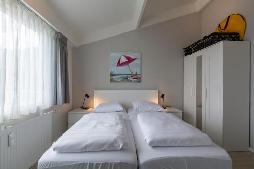 Habitación pequeña con 2 camas y paredes blancas. en Beach appartement 35 Callantsoog, en Callantsoog