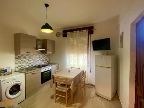 a small kitchen with a table and a refrigerator at Grazioso bilocale in centro in Lotzorai