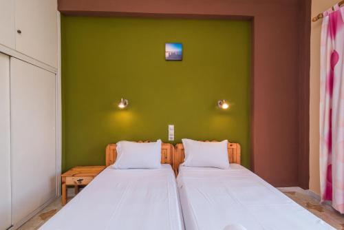 two beds in a room with a green wall at Southgate Apartments in Agios Georgios