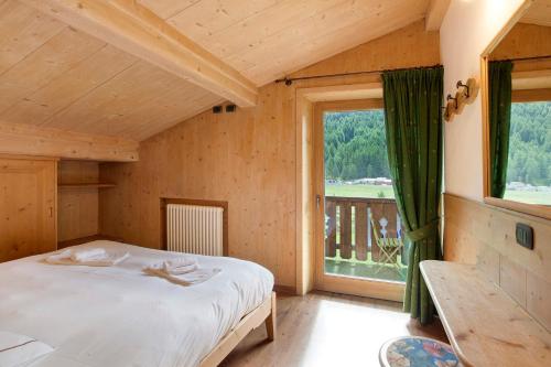 Un dormitorio con una cama y una ventana grande. en Appartamento Castagno Chalet Cambra, en Livigno