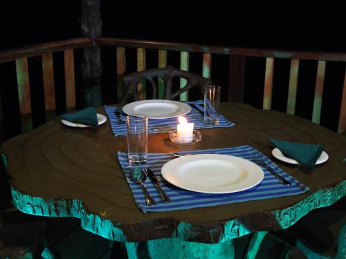 a table with two plates and a candle on it at Sinharaja Forest Edge in Deniyaya