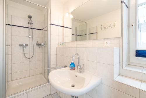 uma casa de banho branca com um lavatório e um chuveiro em Ferienwohnung "Böhler Strandperle" em Sankt Peter-Ording