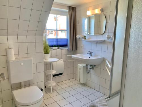 a white bathroom with a toilet and a sink at Zum Leuchtturm - Ferienwohnung 3 in Sankt Peter-Ording