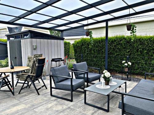a patio with chairs and tables under a pergola at Ferienhaus LuxChalet #VAJU Lathum# am See, Strand, Pool, Nationalpark in Lathum