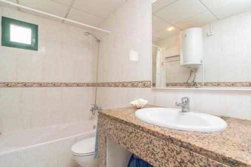 ein Badezimmer mit Waschbecken, Toilette und Spiegel in der Unterkunft Biniforcat 11 in Cala en Forcat