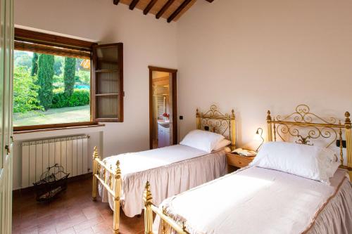 twee bedden in een kamer met een raam bij Via Francigena Cottage in the Green in San Gimignano
