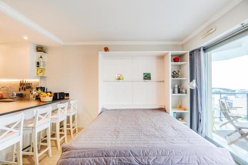 Cet appartement comprend une chambre avec un lit et une cuisine avec une fenêtre. dans l'établissement Le Lido - Piscine, proche plage, à Cagnes-sur-Mer