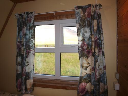 a window with floral curtains in a bedroom at Hömluholt Holiday Homes in Hömluholt