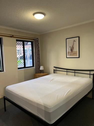Un dormitorio con una gran cama blanca y una ventana. en Spring Hill Gardens Apartments, en Brisbane