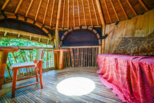 a room with a bed and a chair in a hut at Le Bamboo Bali in Uluwatu